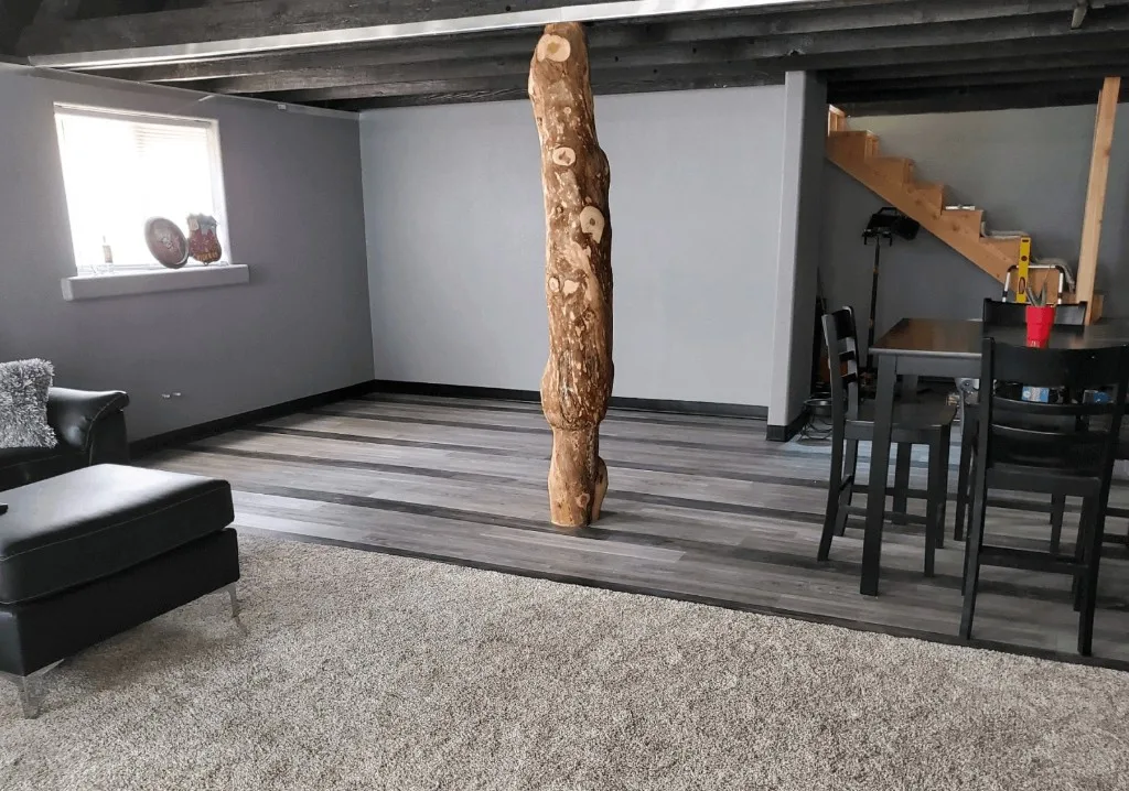 Basement with carpet, grey vinyl plank, and wood log feature